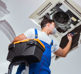 Worker repairing ceiling air conditioning unit